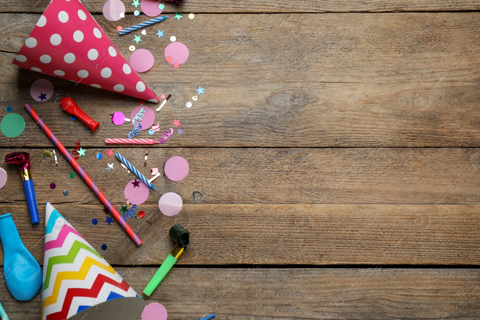 Photo of Colorful party hats and other festive items on wooden table, flat lay. Space for text