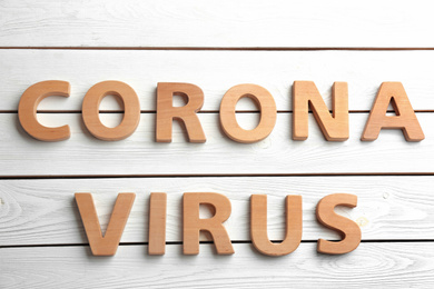 Photo of Words CORONA VIRUS made with wooden letters on white background, flat lay