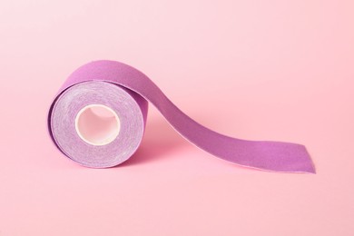 Photo of Bright kinesio tape in roll on pink background