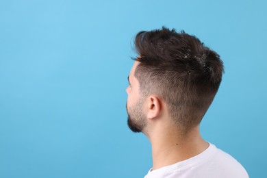 Photo of Man with dandruff in his dark hair on light blue background, space for text