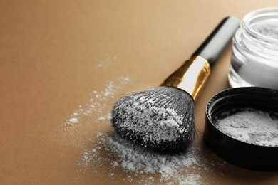 Photo of Makeup brush with white rice loose face powder and lid on brown background, closeup. Space for text