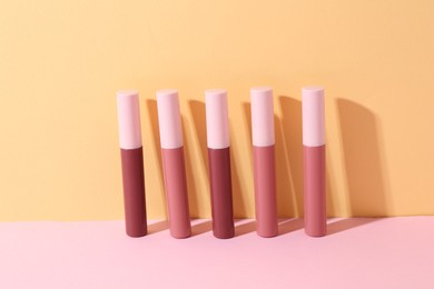 Photo of Many different lip glosses on color background