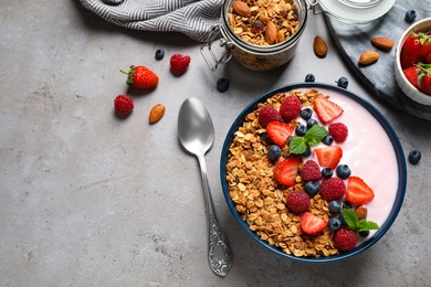 Healthy homemade granola with yogurt on grey table, flat lay. Space for text