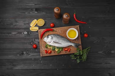 Photo of Flat lay composition with fresh raw dorado fish and spices on black wooden table