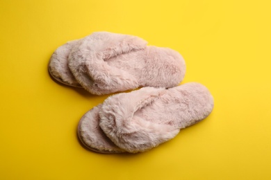 Photo of Pair of stylish soft slippers on yellow background