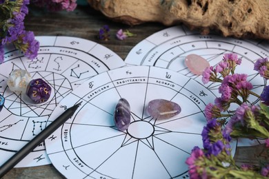Photo of Zodiac wheels, gemstones, flowers and astrology dices on wooden table, closeup