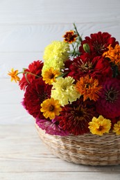 Beautiful wild flowers in wicker basket on light wooden table