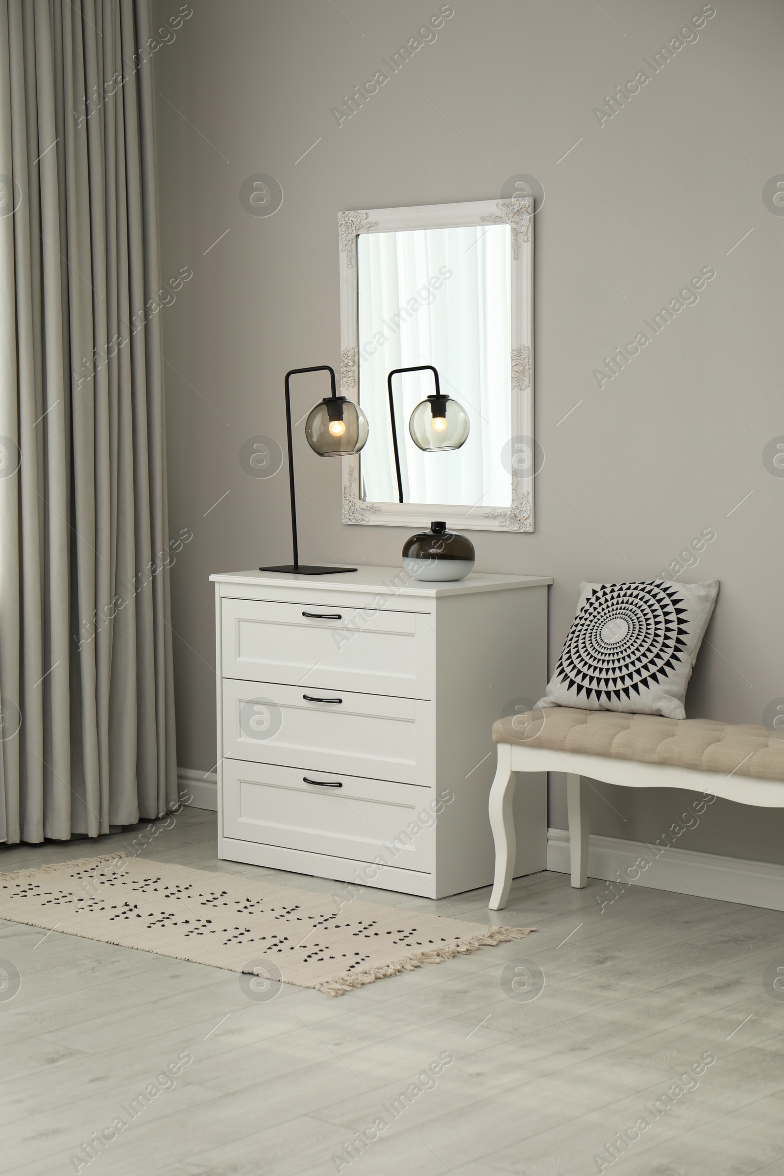 Photo of Hallway with stylish chest of drawers and mirror. Interior design