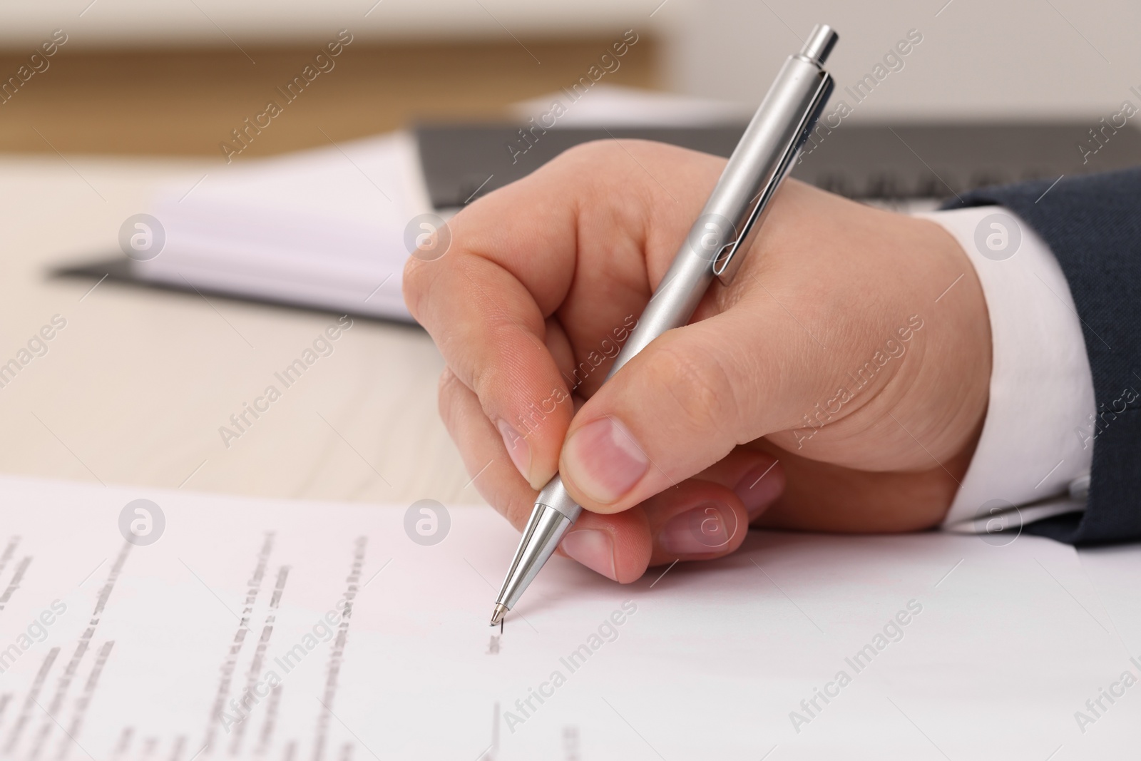 Photo of Man signing document at table, closeup view