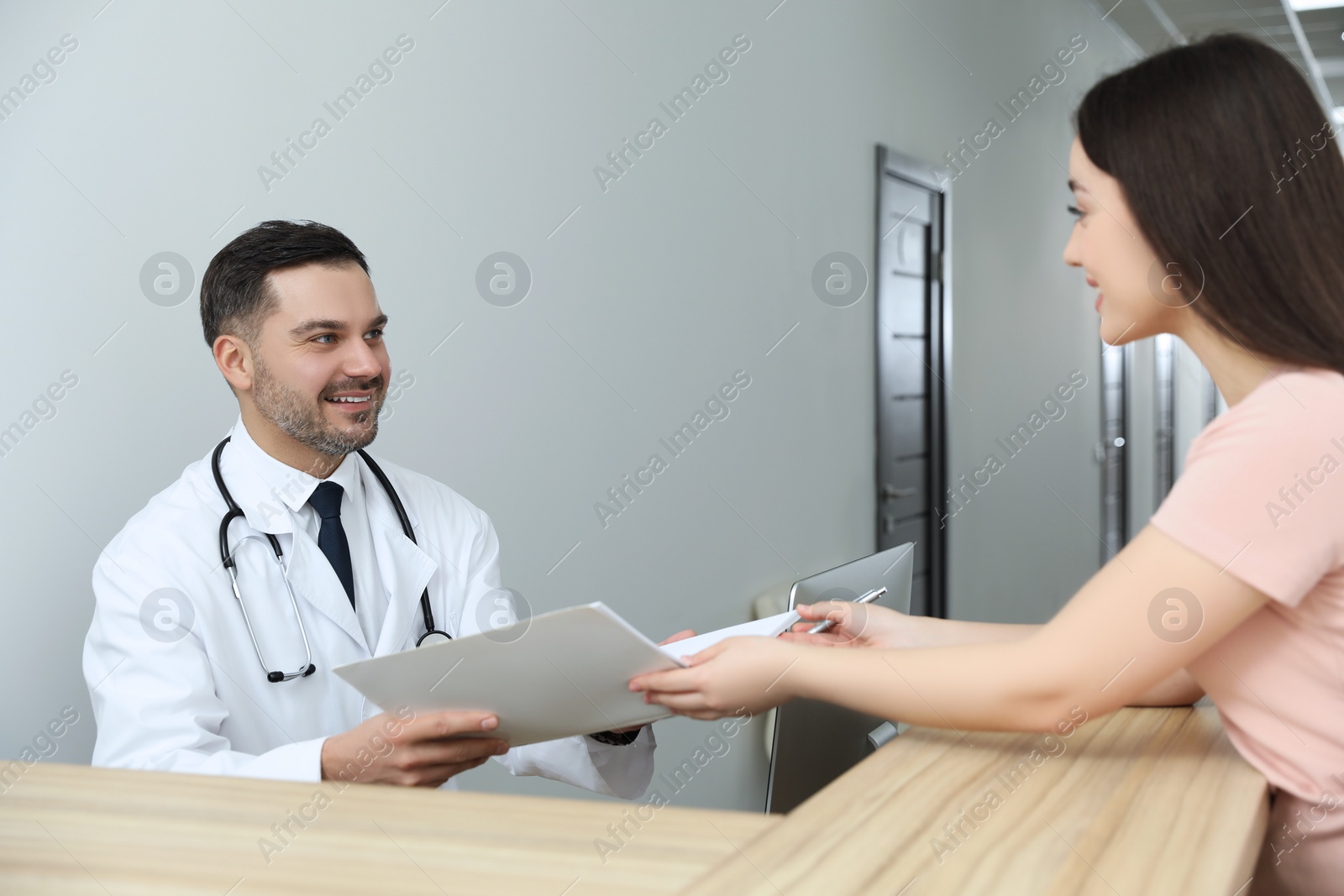 Photo of Doctor with notebook consulting patient in clinic