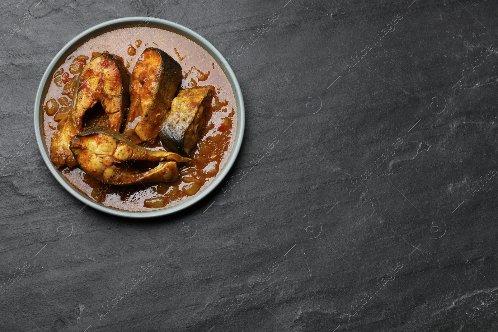 Photo of Tasty fish curry on grey textured table, top view. Space for text. Indian cuisine