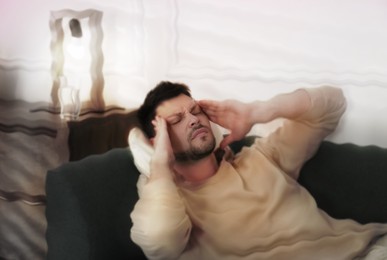 Image of Man suffering from migraine on sofa at home