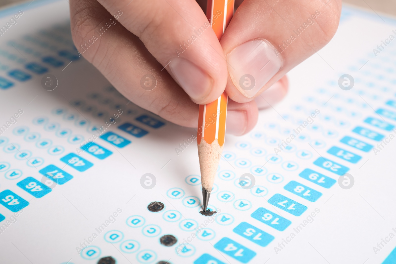 Photo of Student filling answer sheet at table, closeup. Passing exam