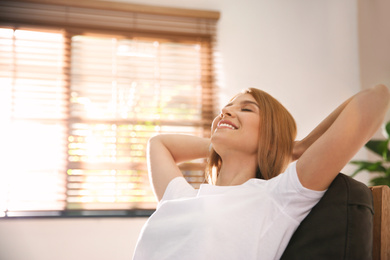 Photo of Young woman relaxing in armchair near window at home. Space for text