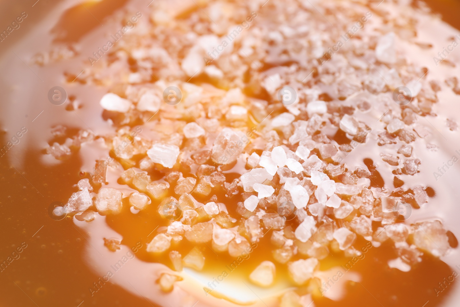 Photo of Delicious caramel sauce with sea salt as background, closeup