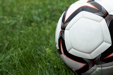 Photo of New soccer ball on fresh green grass outdoors, closeup