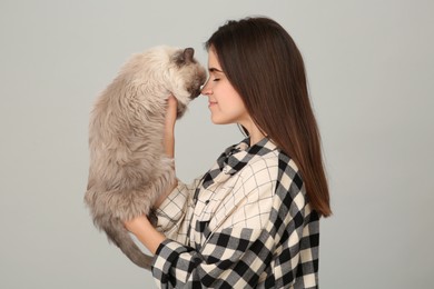 Photo of Woman with her cute cat on light grey background