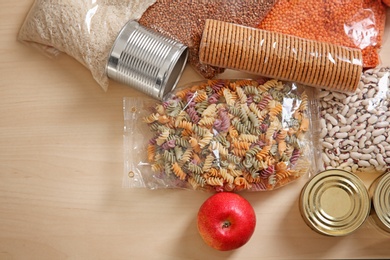 Photo of Many different products and space for text on wooden background, flat lay. Food donation