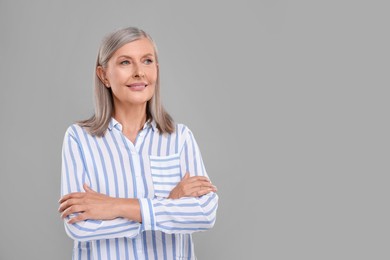 Portrait of beautiful middle aged woman on light grey background, space for text