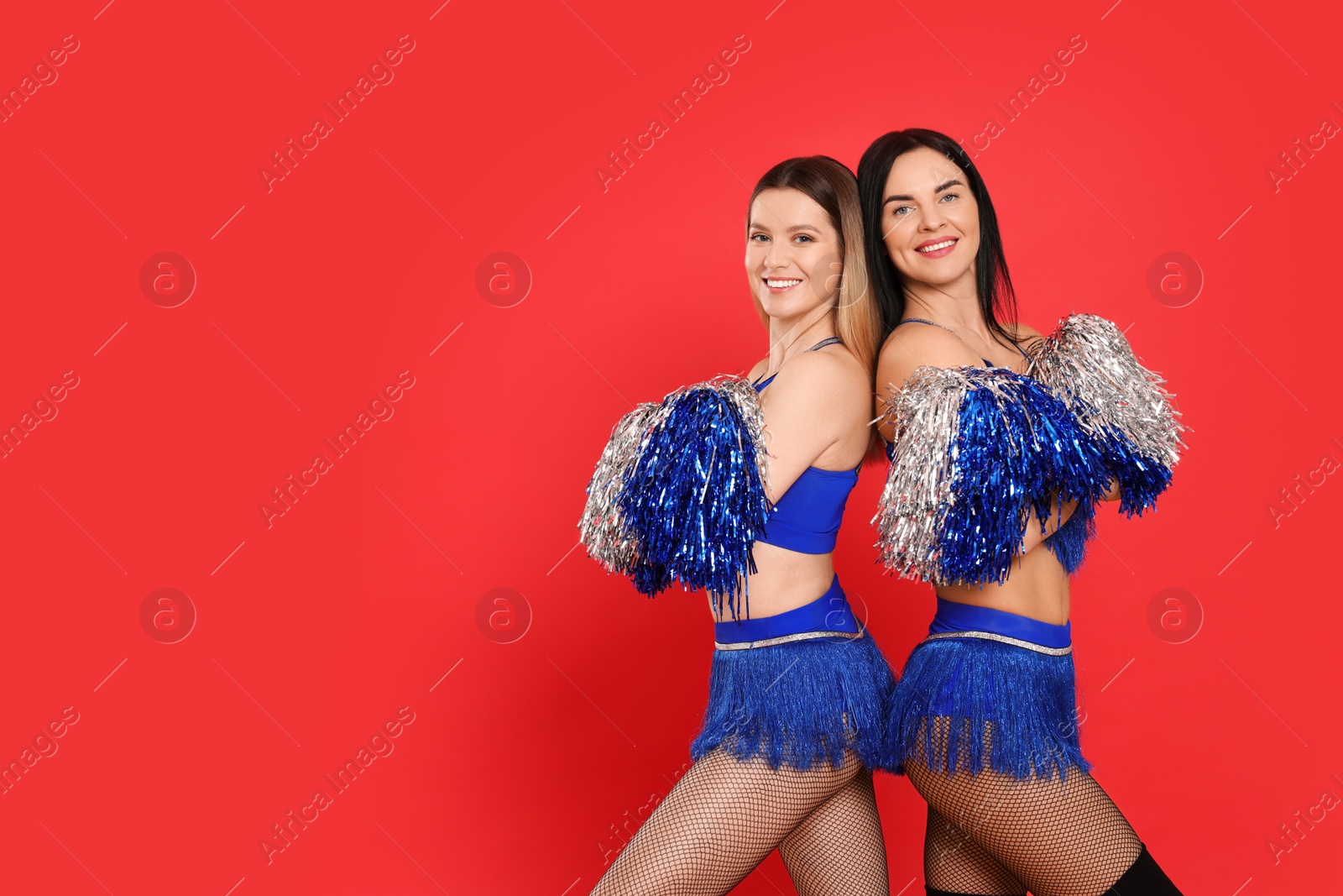 Photo of Beautiful young cheerleaders on red background. Space for text