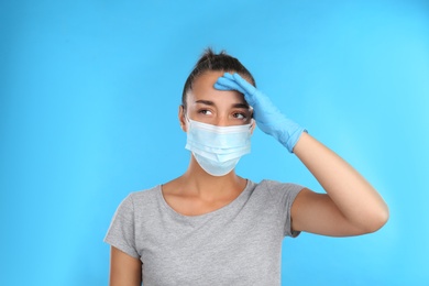 Photo of Stressed woman in protective mask on light blue background. Mental health problems during COVID-19 pandemic