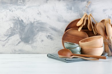 Photo of Different dishware and utensils on white marble table against textured wall. Space for text