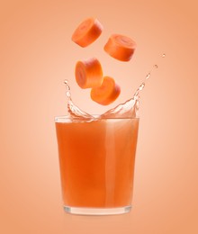 Image of Splashing freshly made carrot juice on coral background. Cut carrot falling into glass