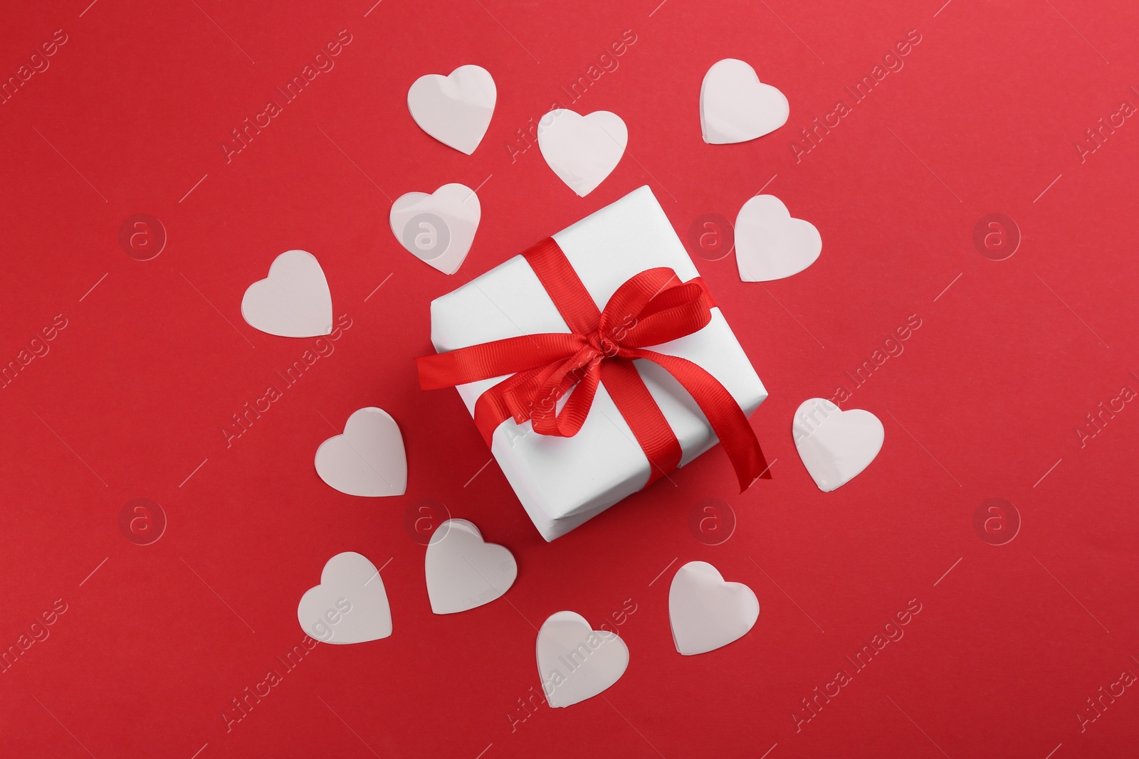 Photo of Beautiful gift box and hearts on red background, flat lay. Valentine's day celebration