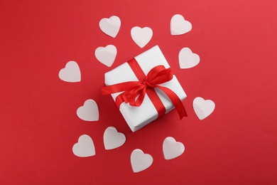 Beautiful gift box and hearts on red background, flat lay. Valentine's day celebration