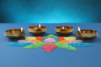 Photo of Diwali celebration. Diya lamps and colorful rangoli on blue background
