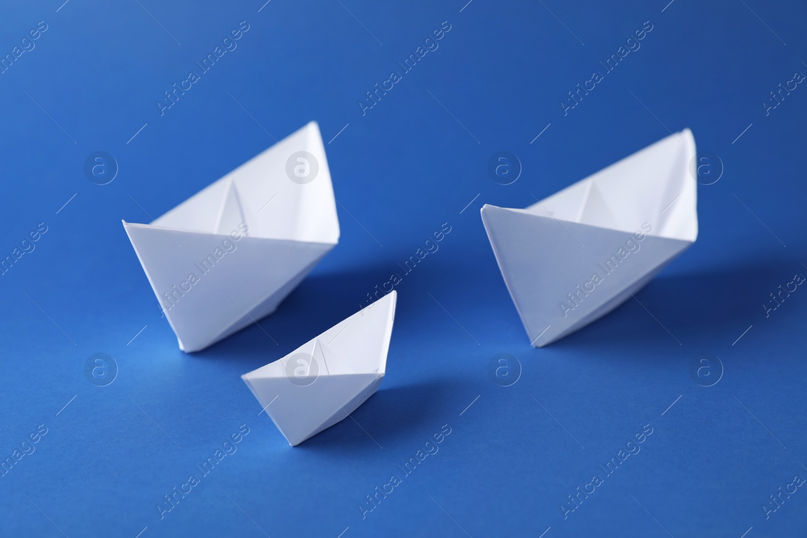 Photo of Handmade paper boats on blue background. Origami art