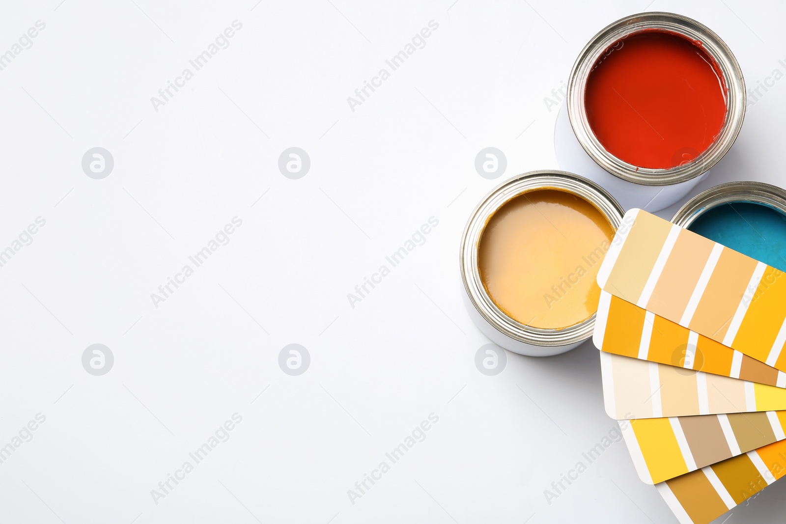 Photo of Paint cans and color palette on white background, top view. Space for text