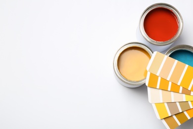 Photo of Paint cans and color palette on white background, top view. Space for text