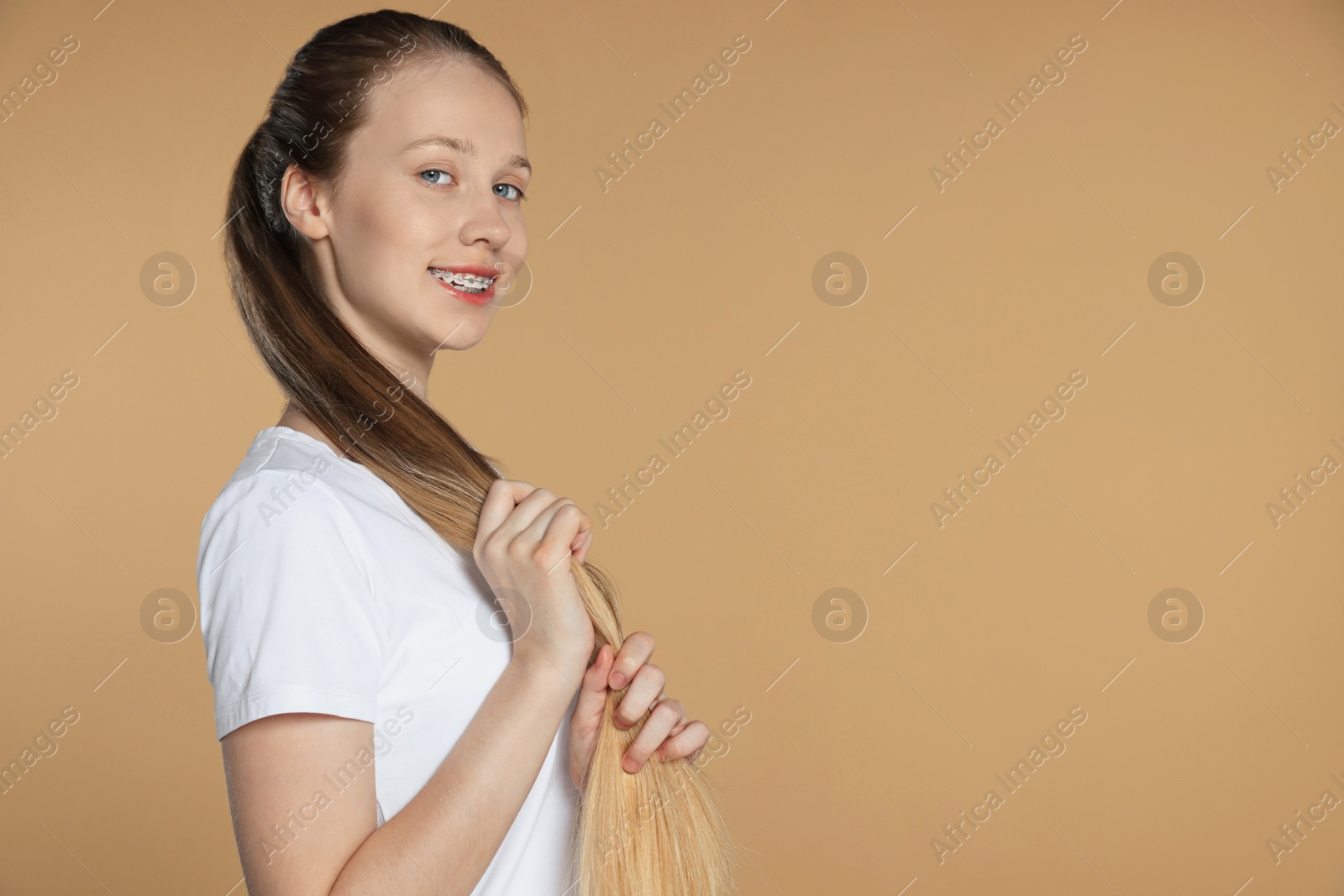 Photo of Teenage girl with strong healthy hair on beige background, space for text