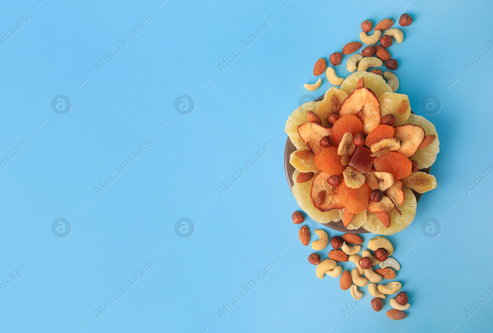 Photo of Mixed dried fruits and nuts on light blue background, flat lay. Space for text