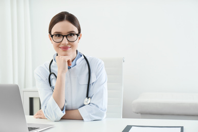 Portrait of young female doctor in white coat at workplace