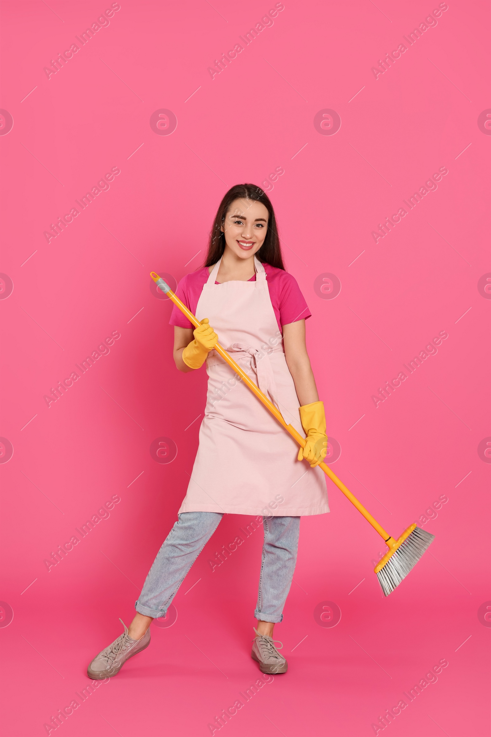 Photo of Beautiful young woman with broom on pink background