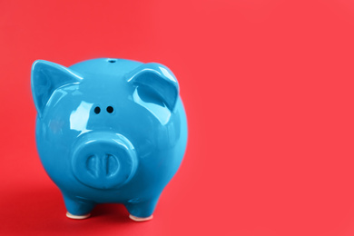 Photo of Blue piggy bank on red background. Space for text