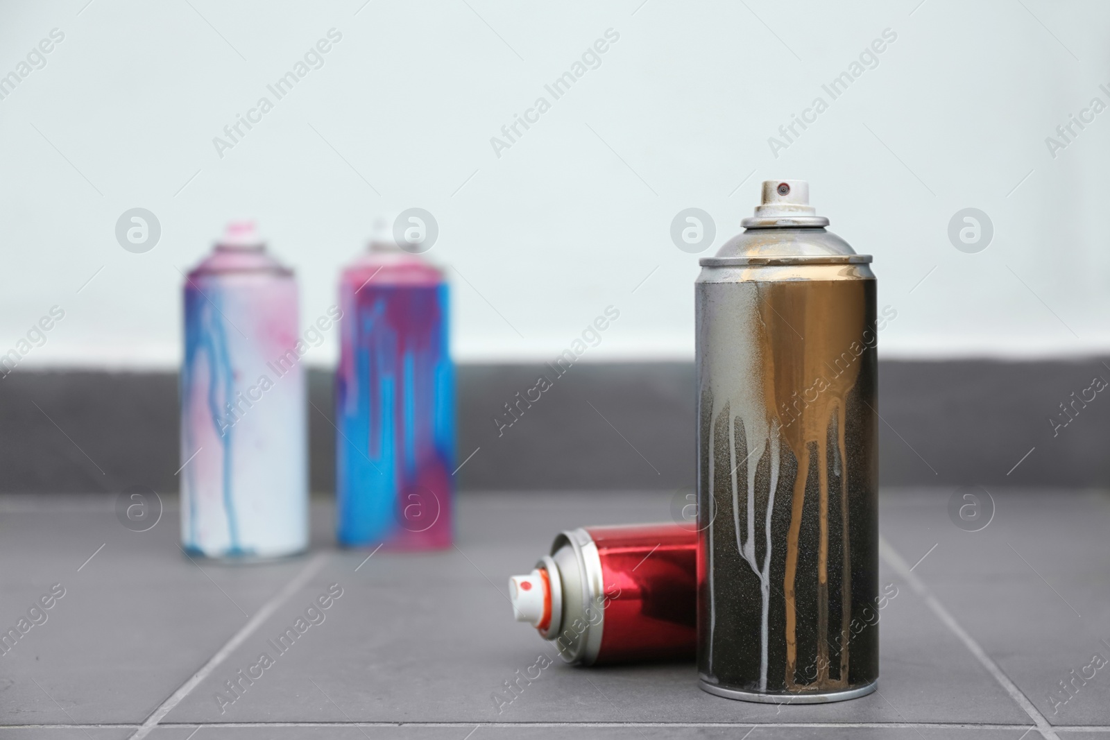 Photo of Used cans of spray paint on floor indoors. Space for text