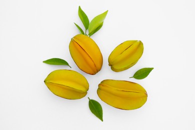 Photo of Delicious whole carambolas and green leaves on white background, top view