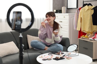 Photo of Smiling beauty blogger recording makeup tutorial at home