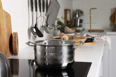 Photo of Metal pot on cooktop in kitchen. Cooking utensils