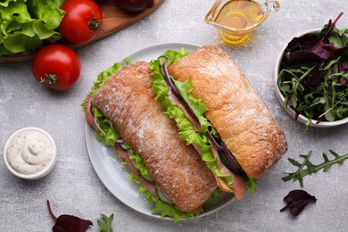 Photo of Delicious sandwiches with salmon and ingredients on light gray table, flat lay