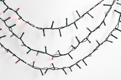 Photo of Beautiful Christmas lights on white background, top view