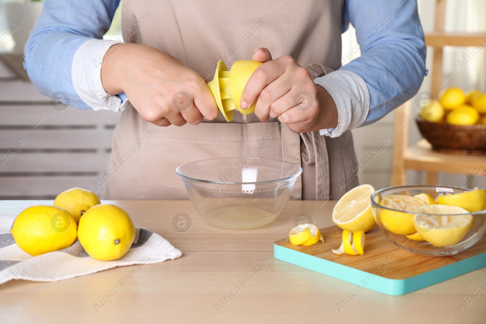 Photo of Woman squeezing lemon juice with reamer at wooden table, closeup