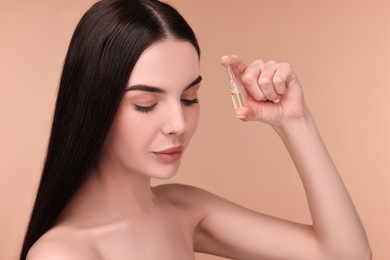 Photo of Beautiful young woman holding skincare ampoule on beige background