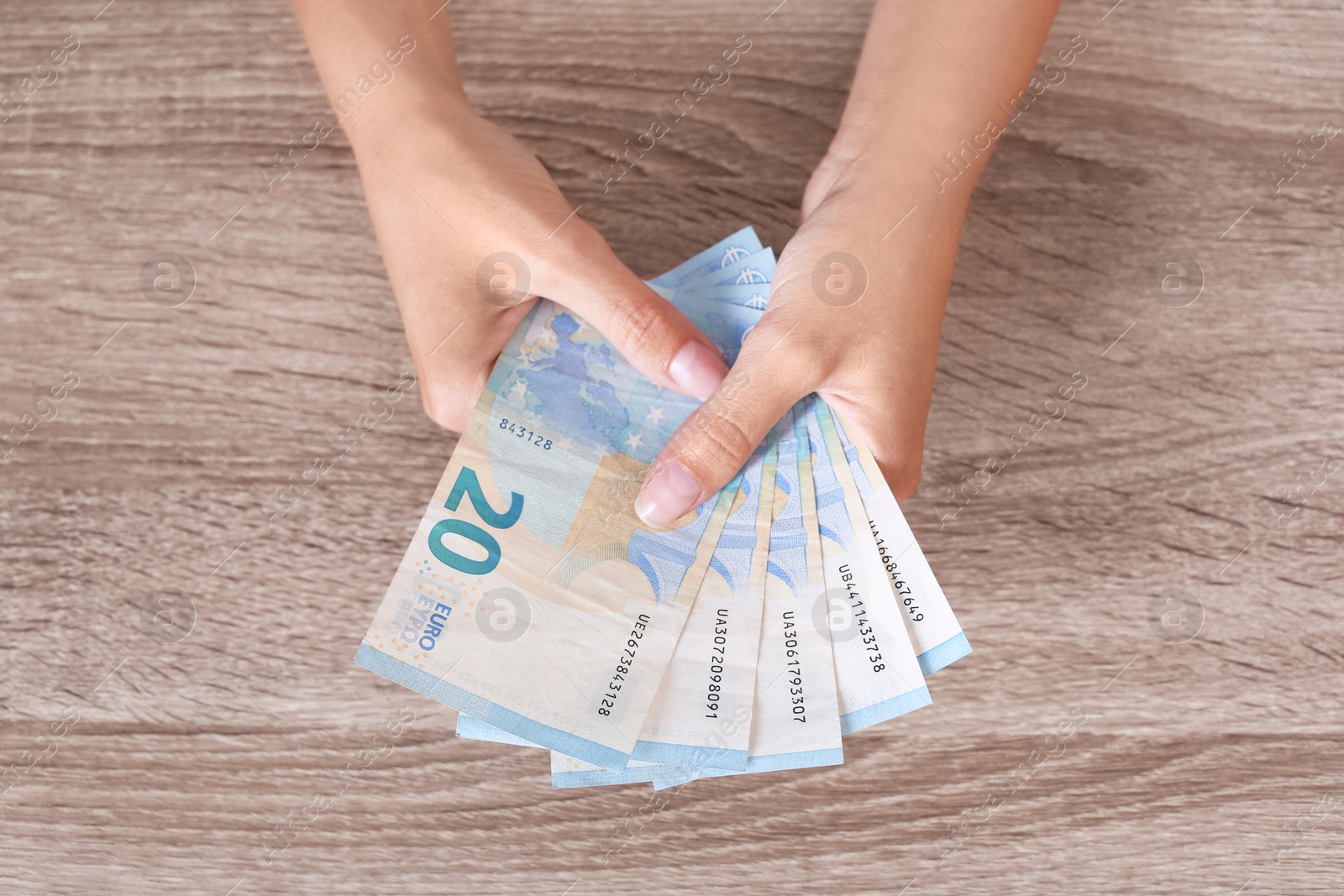 Photo of Woman with Euro banknotes at wooden table, top view