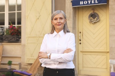 Smiling business owner near her hotel outdoors