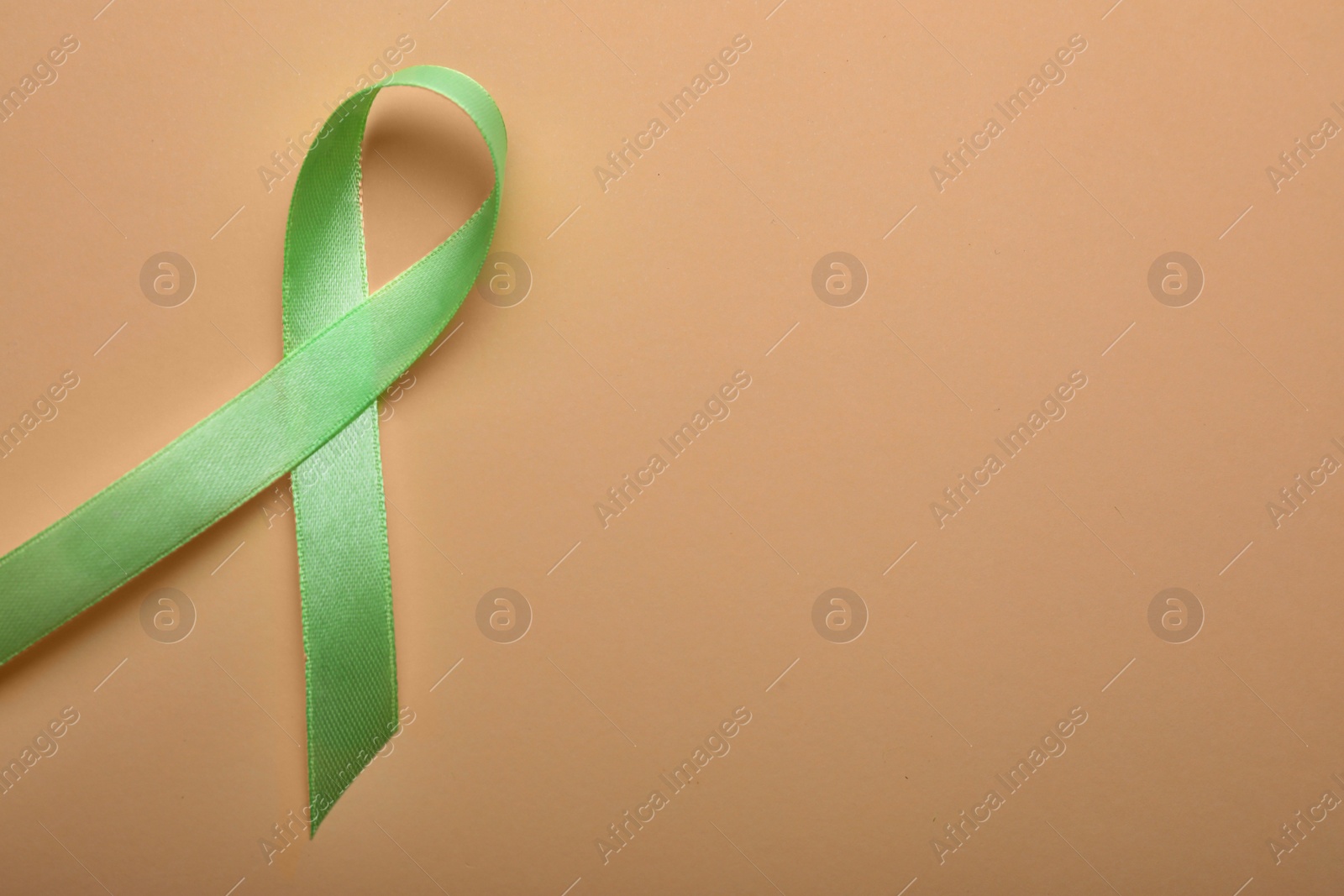 Photo of World Mental Health Day. Green ribbon on color background, top view with space for text