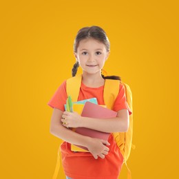 Image of Cute child with school stationery on yellow background